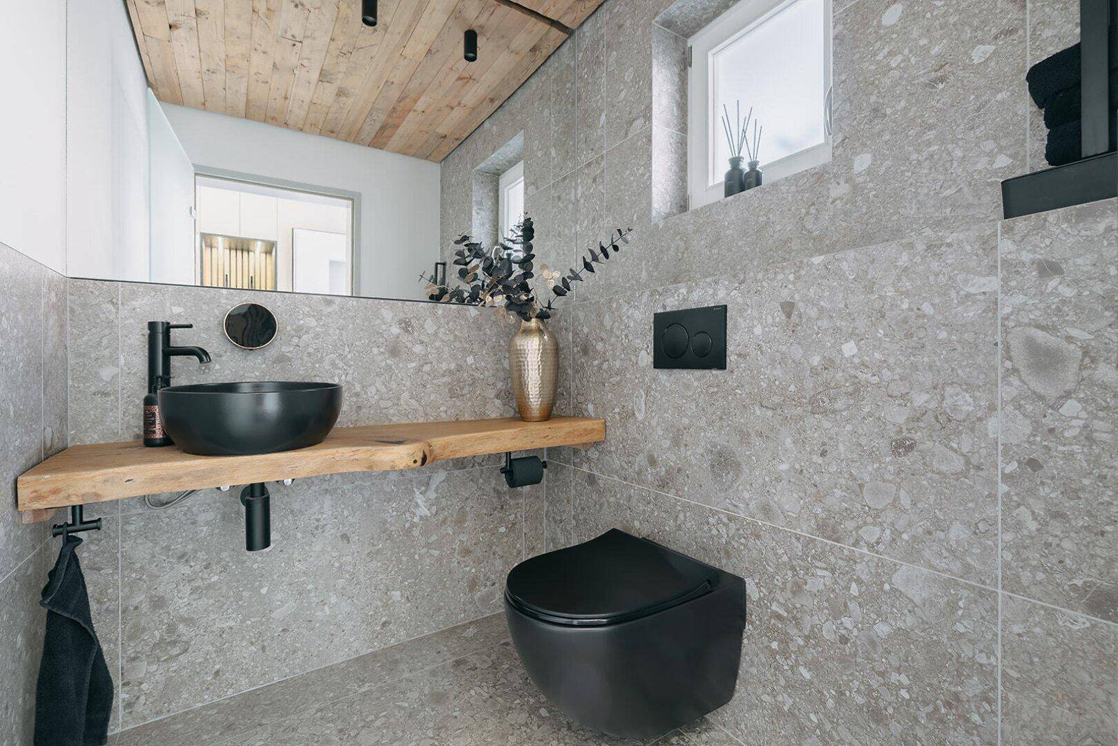 Modernes Gäste-WC mit Holzdecke, schwarzem Waschbecken und Wand-WC.