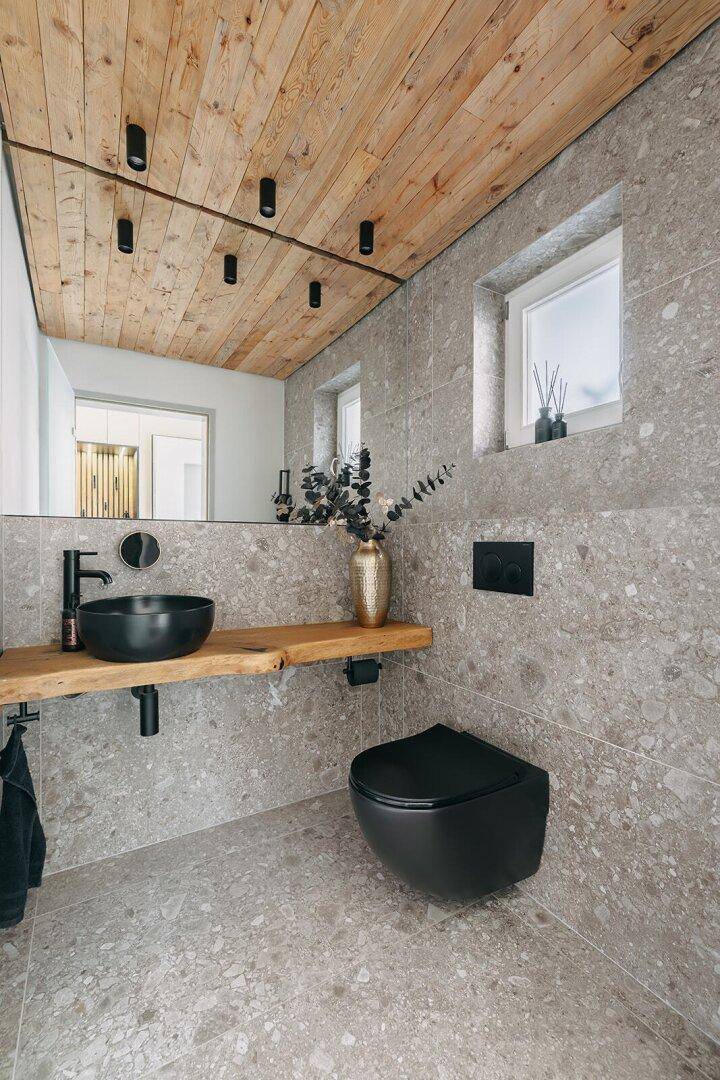 Modernes Gäste-WC mit Holzdecke, schwarzem Waschbecken und Wand-WC.