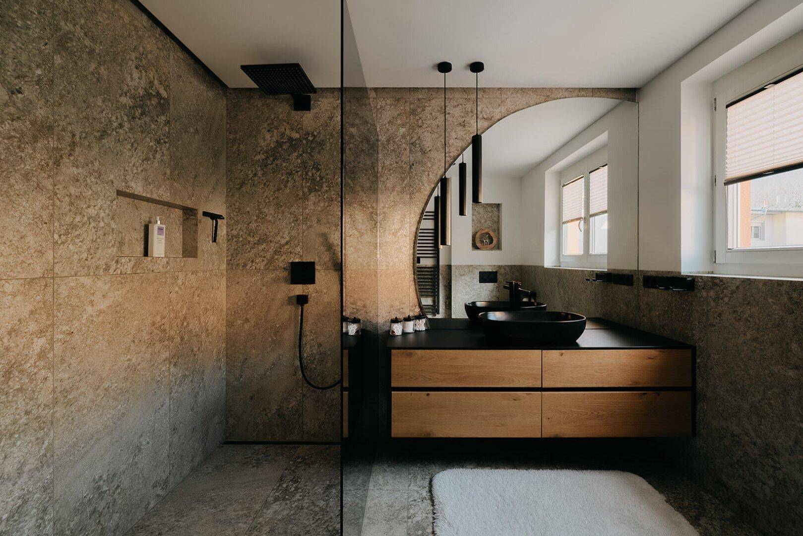 Modernes Badezimmer mit begehbarer Dusche, Natursteinfliesen und stilvollem Holzwaschtisch.