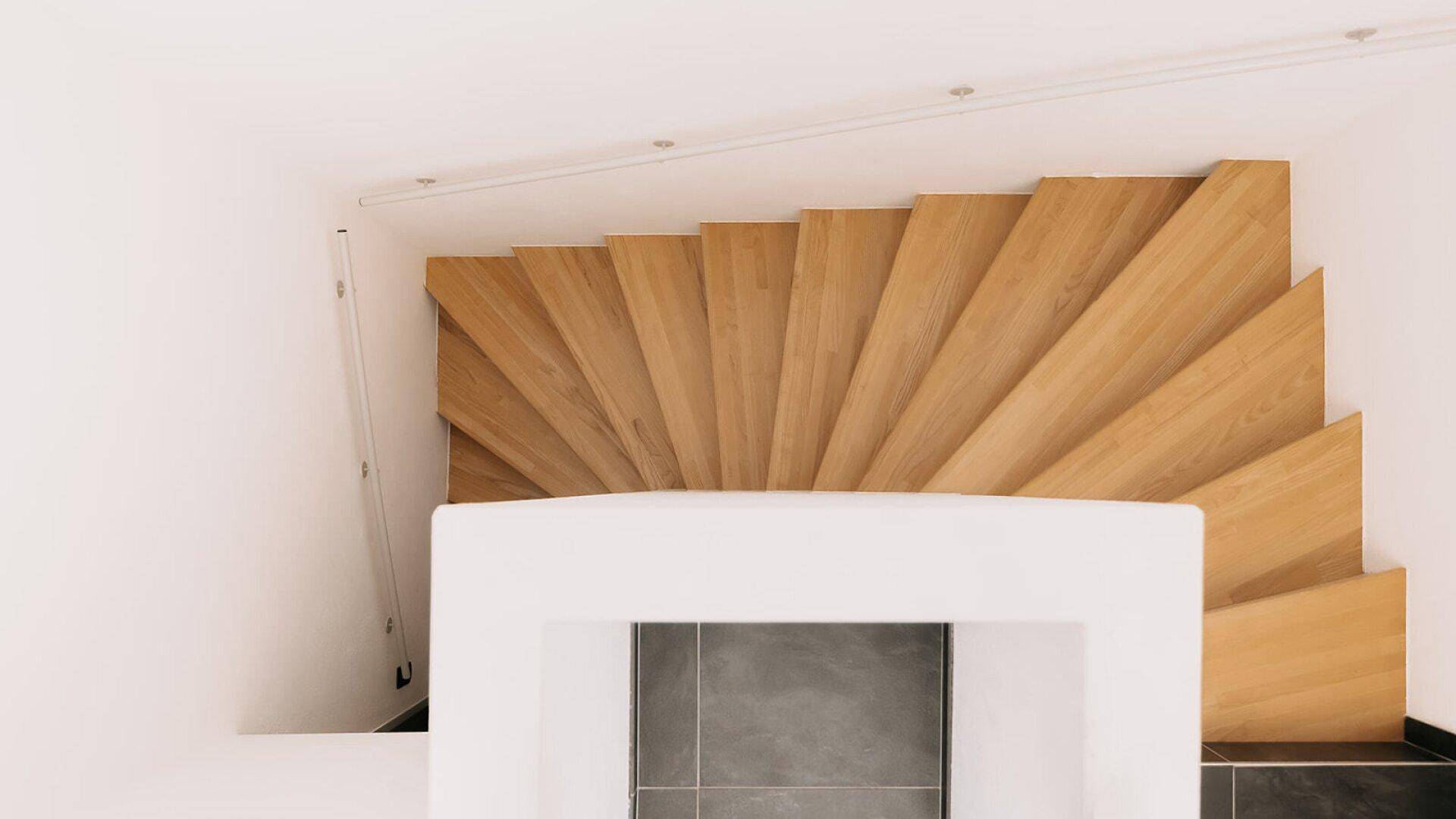 Elegante Holztreppe von oben gesehen, die die verschiedenen Ebenen des Hauses verbindet.