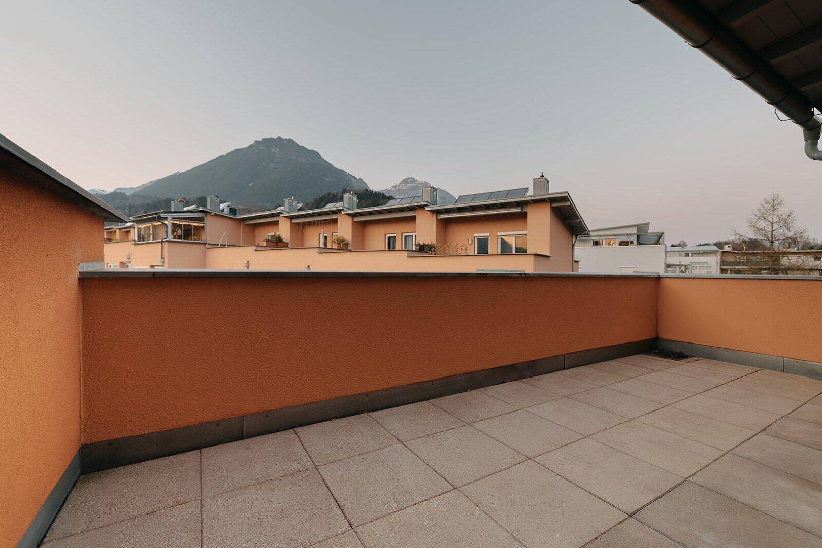 Weitläufige Dachterrasse mit Fliesenboden und Panoramablick auf die umliegende Berglandschaft.