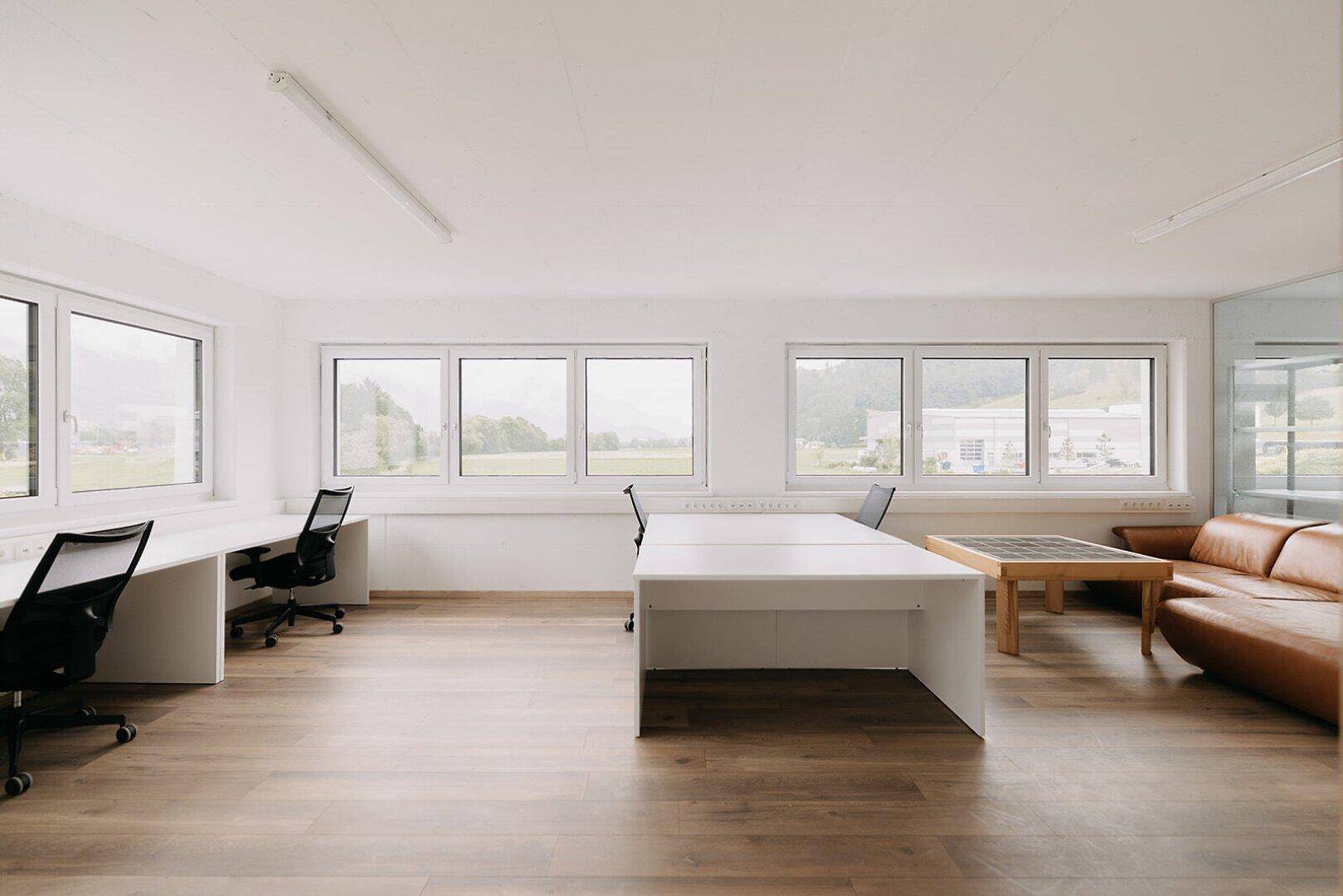 Helles Büro mit Holzboden, modernen Arbeitsplätzen und großen Fenstern mit Weitblick.