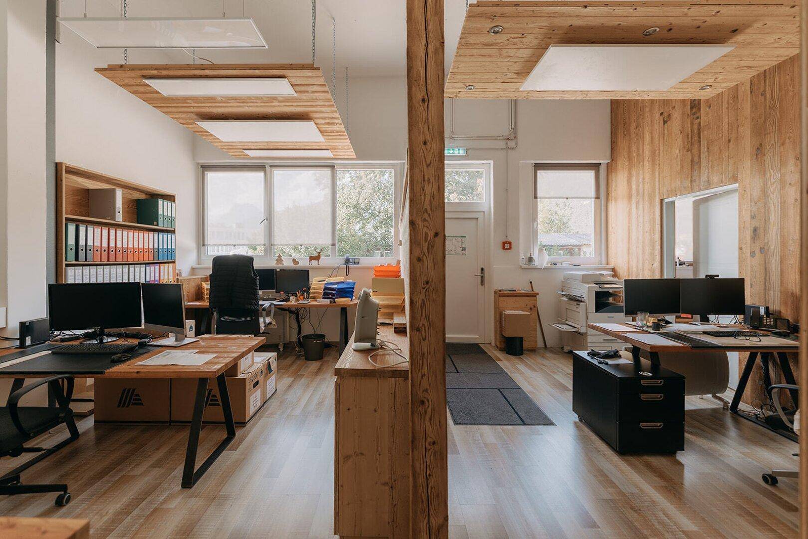 Modernes Büro mit Holzelementen, mehreren Arbeitsplätzen und viel natürlichem Licht.