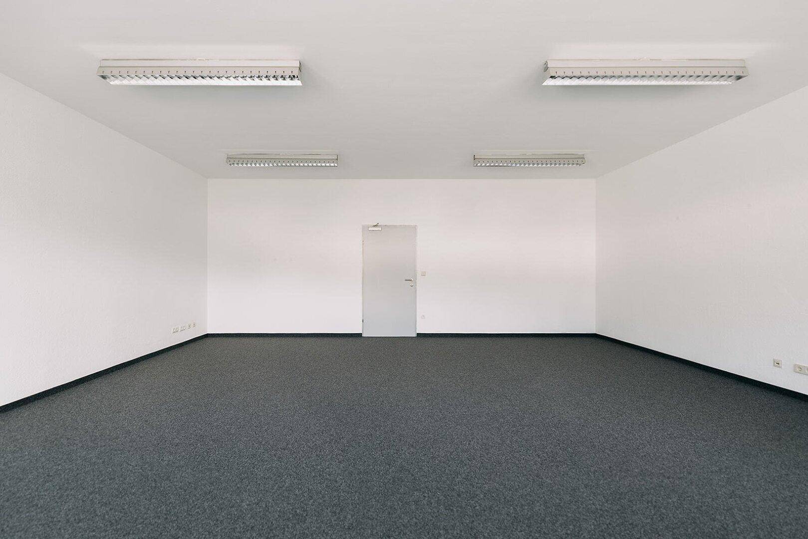 Leeres Büro mit Teppichboden und einer einfachen Tür, bereit zur individuellen Gestaltung.