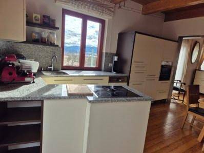 Moderne Küche mit Granitarbeitsplatten, Induktionskochfeld und Fenster mit Bergblick.