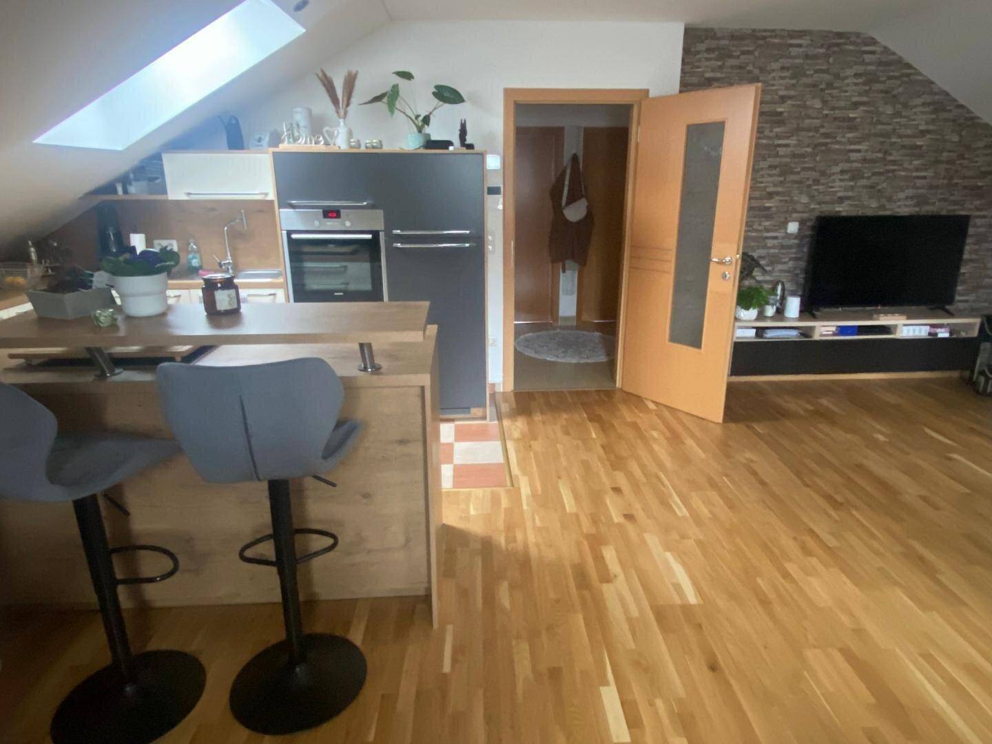 Offener Wohnbereich mit Holzboden, moderner Küchenzeile und Dachfenster, ideal für Loft-Feeling.
