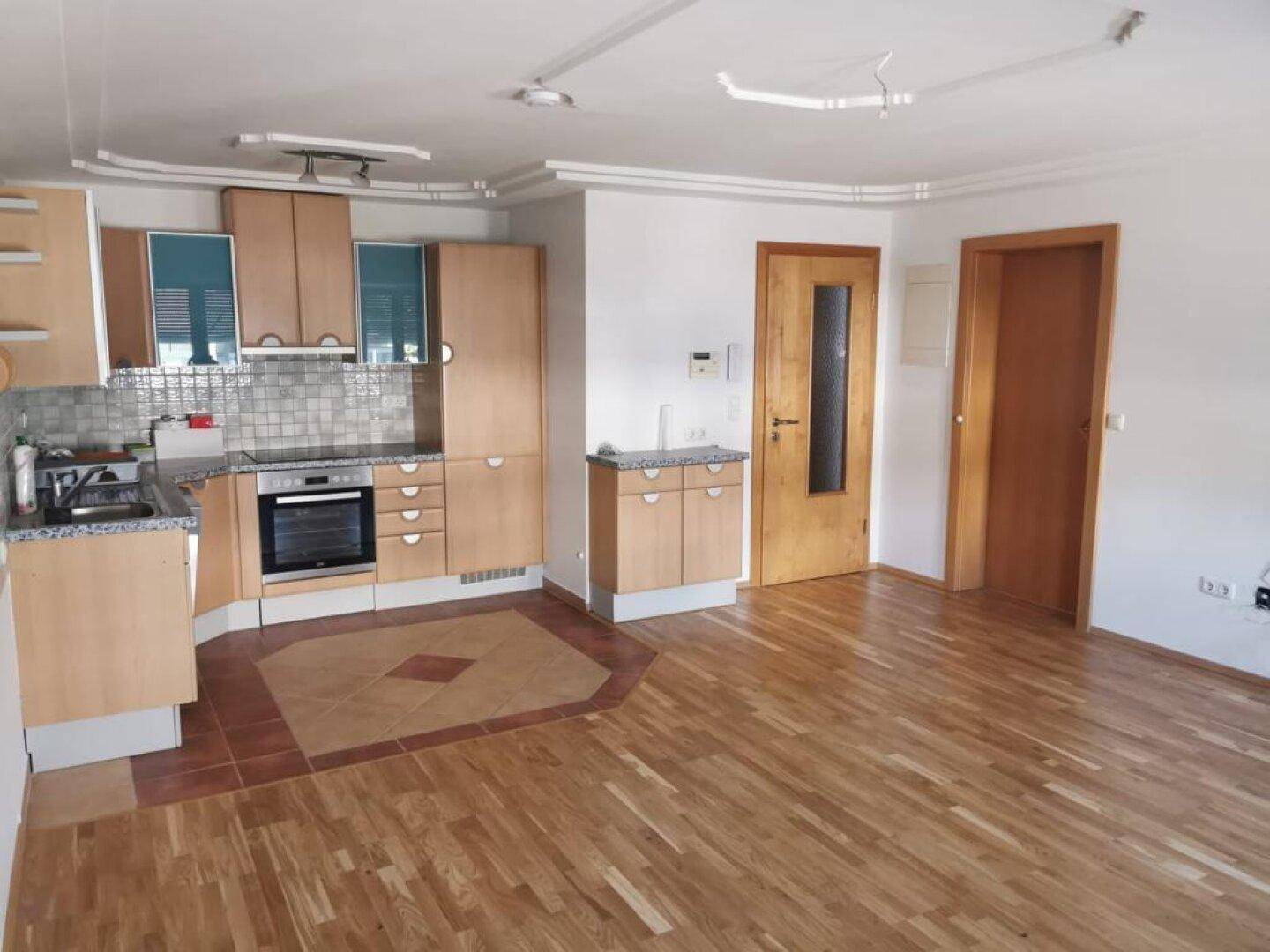 Geräumiger Wohnbereich mit offener Küche, Holzboden und Deckenstuck, ideal für Familien.