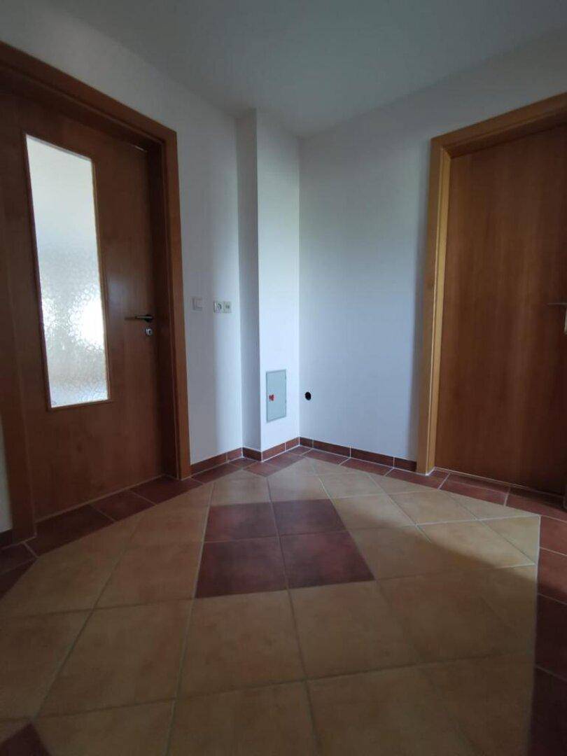 Heller Flur mit Fliesenboden und Holztüren, der zu verschiedenen Räumen der Wohnung führt.