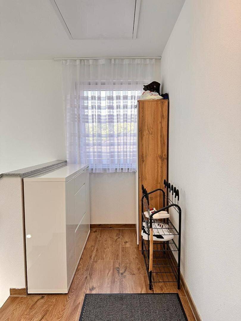 Heller Flur mit Fenster, Schuhregal und praktischem Schrank für zusätzlichen Stauraum.