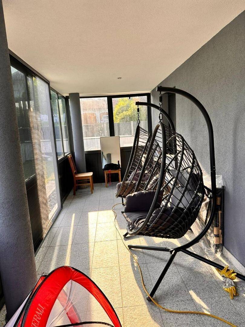 Überdachter Balkon mit bequemen Hängesesseln und viel Tageslicht, perfekt zum Entspannen.