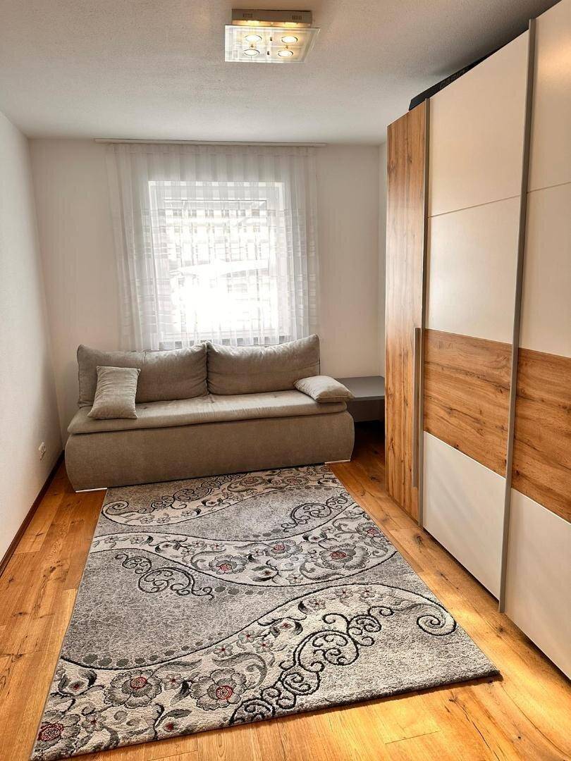 Helles Zimmer mit Schlafsofa, großem Kleiderschrank und Parkettboden.