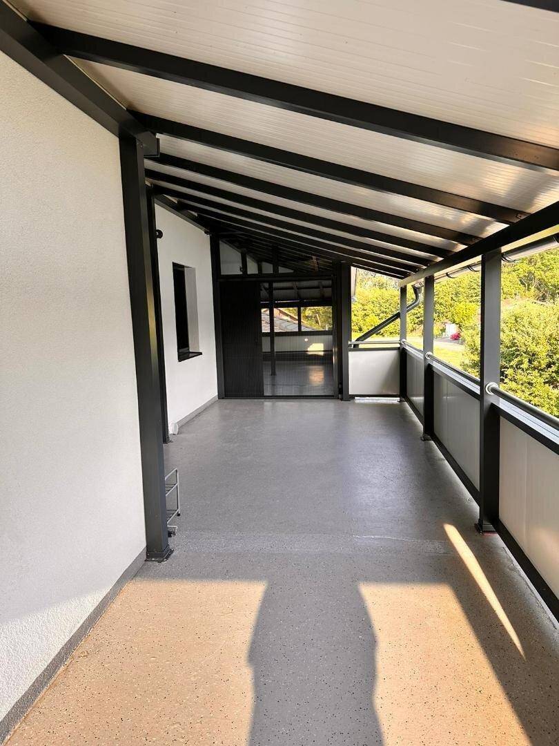 Geräumiger überdachter Balkon mit Blick ins Grüne, ideal für entspannte Stunden im Freien.