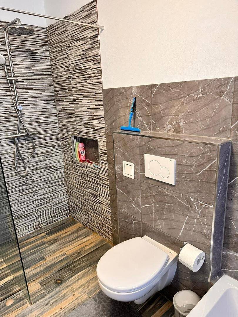 Modernes Badezimmer mit ebenerdiger Dusche, Wand-WC und stilvollen Fliesen.