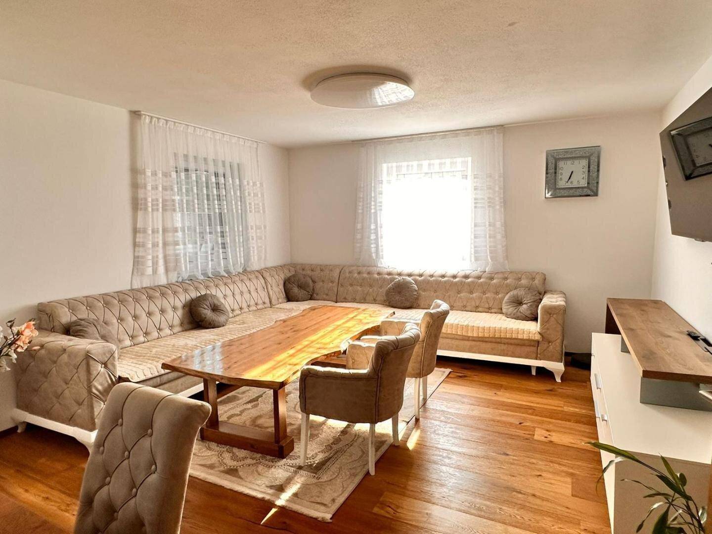Gemütlicher Wohnbereich mit großem Ecksofa, rustikalem Holztisch und viel Tageslicht.