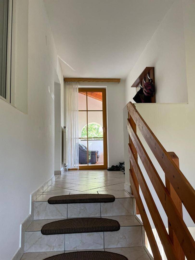 Heller Treppenabsatz mit Fliesenboden und Zugang zu einem Balkon.