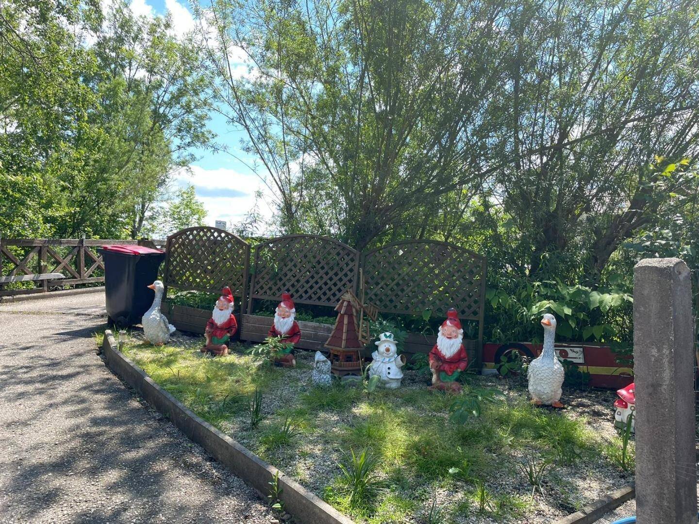 Gartenbereich mit Rasen, Büschen und dekorativen Gartenzwergen und Tierfiguren.