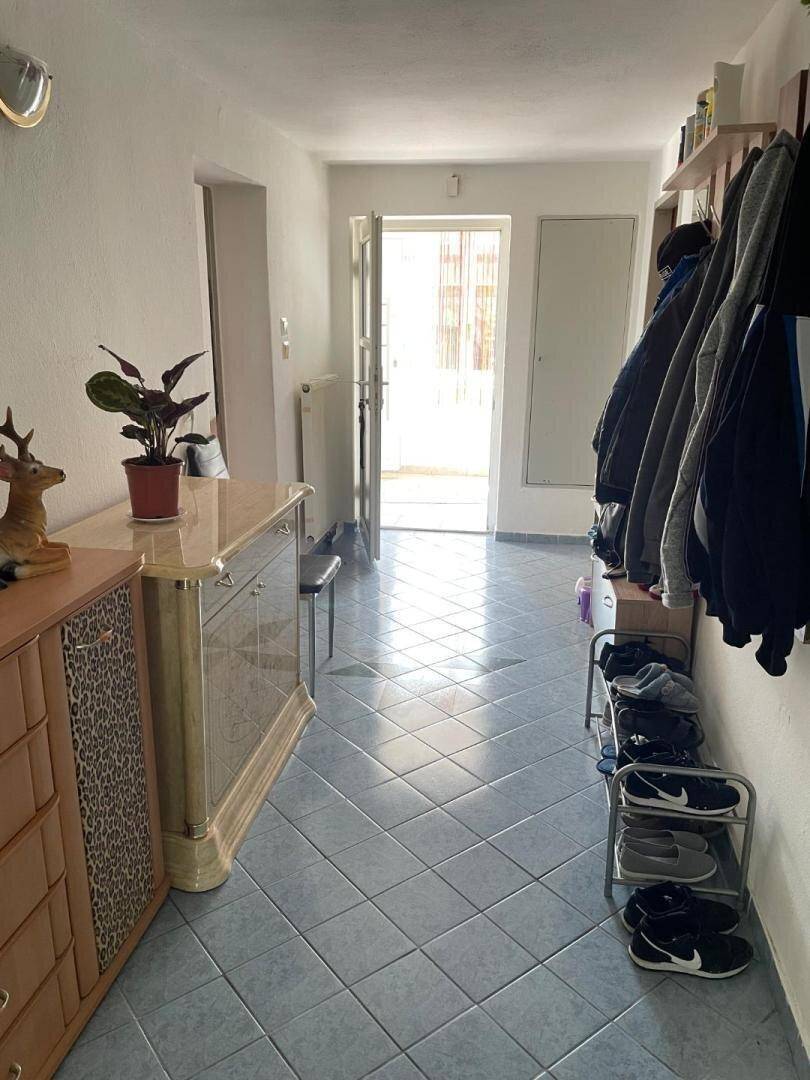 Heller Eingangsbereich mit hellblauen Fliesen, Garderobe und Kommode.