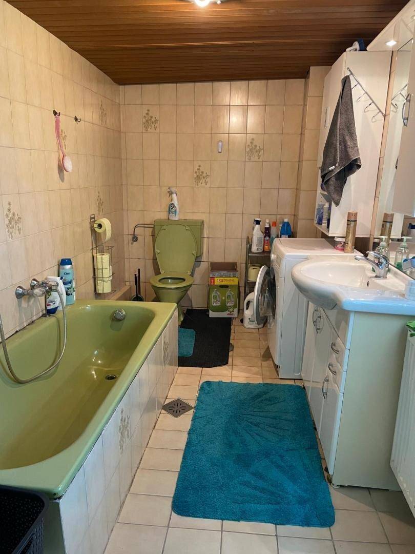 Badezimmer mit grüner Badewanne, passender Toilette und Waschmaschine.