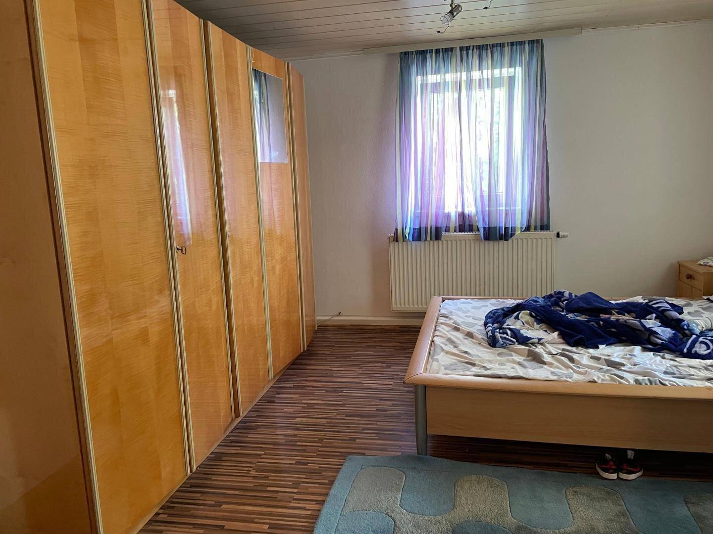 Schlafzimmer mit großem Kleiderschrank, Bett und Laminatboden.