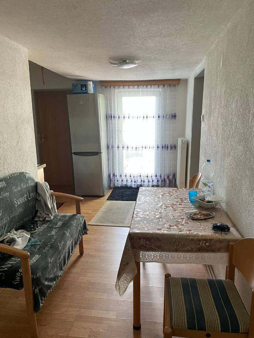 Essbereich mit Holztisch, Stühlen und Fenster, ausgestattet mit einem Kühlschrank.