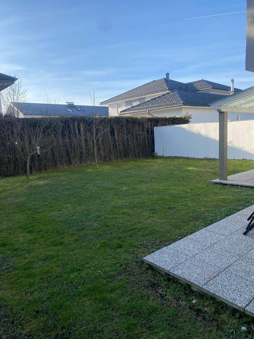 Gepflegter Gartenbereich mit Rasenfläche und hoher Hecke als natürlicher Sichtschutz.