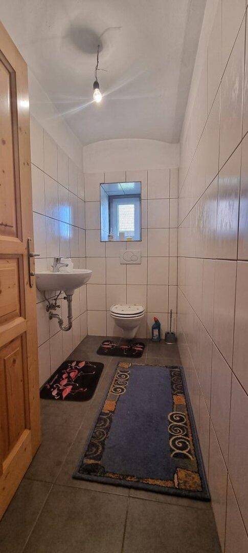Kleines WC mit gefliesten Wänden, Waschbecken und Toilette.