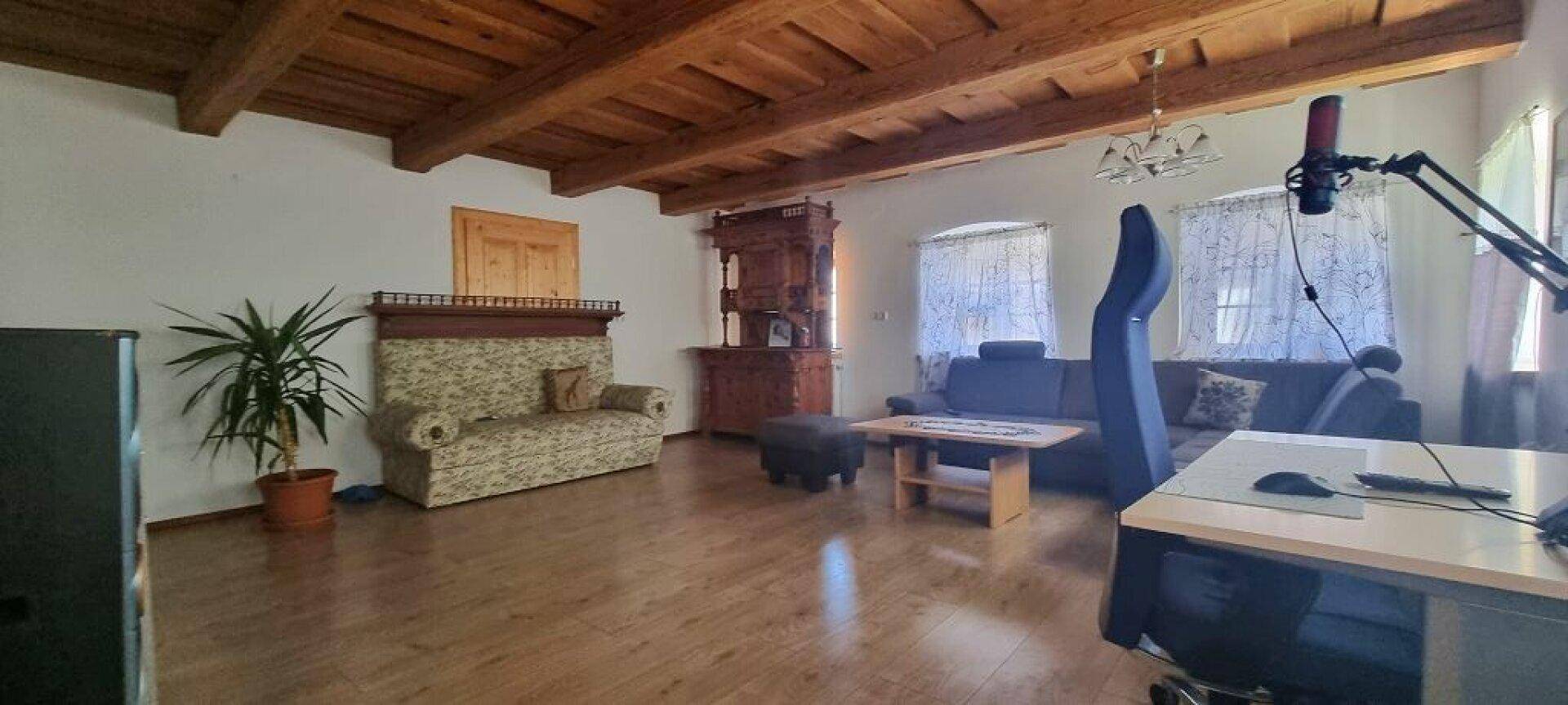 Gemütliches Wohnzimmer mit Holzboden, sichtbaren Deckenbalken und traditionellen Möbeln.