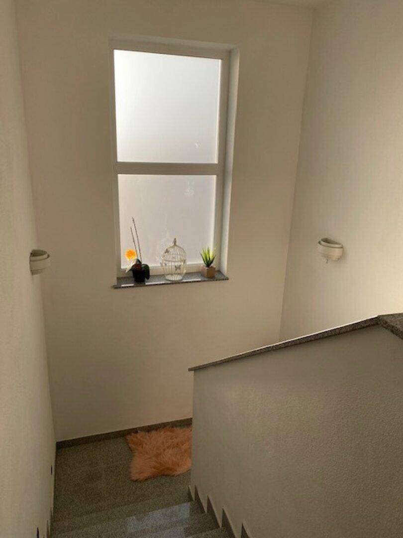 Treppenabsatz mit einem blickdichten Fenster und dekorativen Elementen, die für eine angenehme Atmosphäre sorgen.