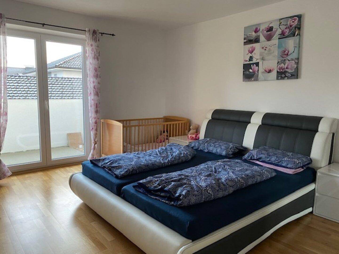 Gemütliches Schlafzimmer mit Doppelbett, Babybett und direktem Zugang zu einem Außenbereich.