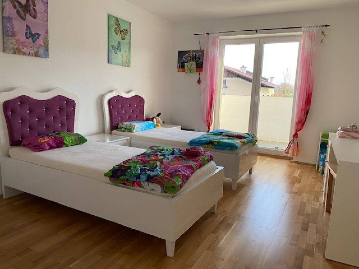 Freundliches Kinderzimmer mit zwei Betten, lebhafter Dekoration und direktem Balkonzugang.