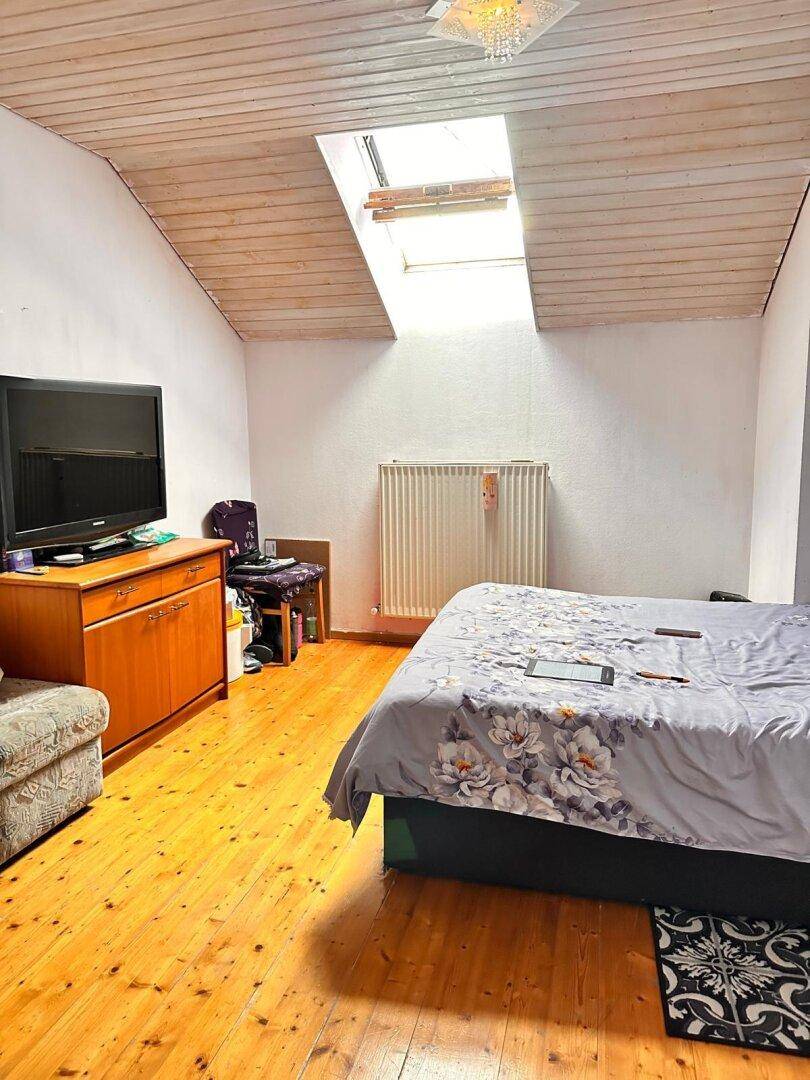 Schlafzimmer im Dachgeschoss mit Holzboden, Dachschräge und einem Dachfenster.