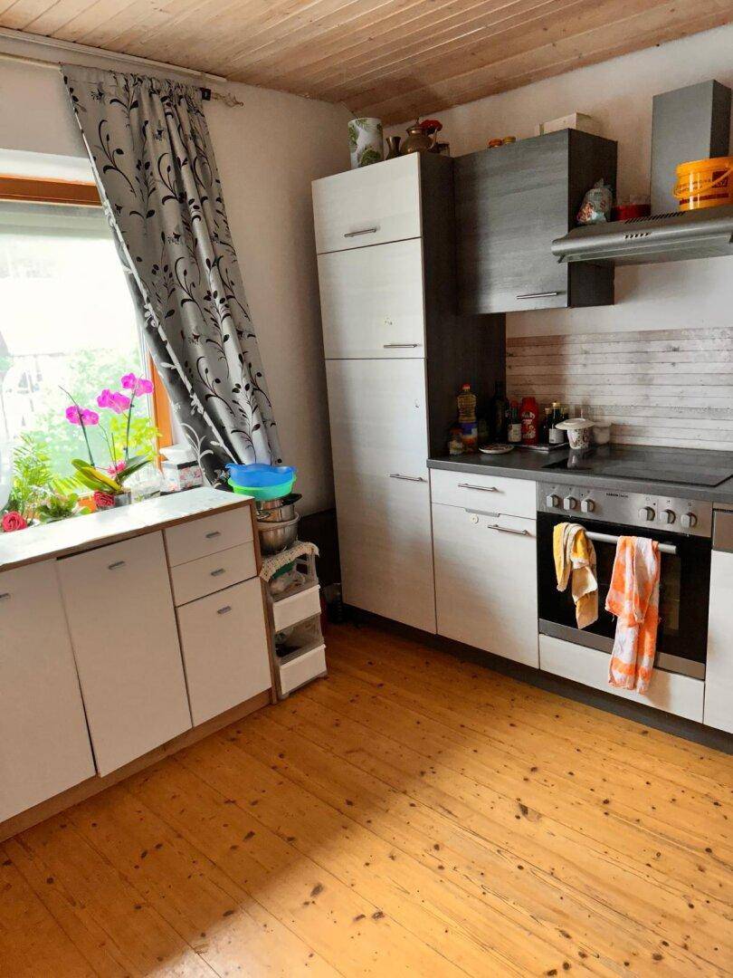 Kleine Küche mit hellen Schränken, Fenster und Orchideen auf der Fensterbank.