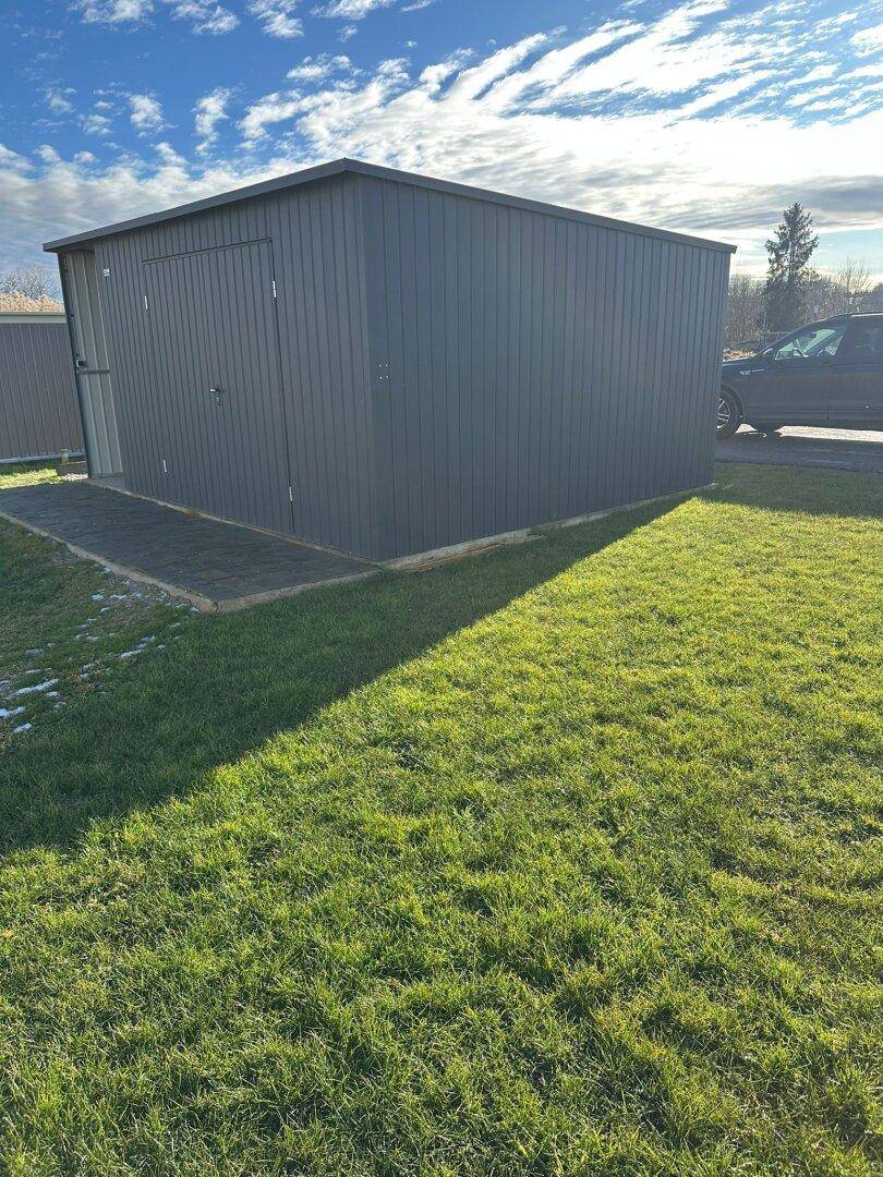 Praktischer Gartenschuppen auf einer grünen Rasenfläche für zusätzlichen Stauraum.