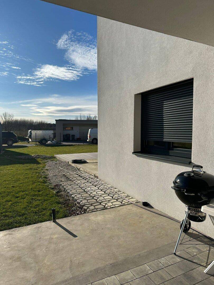 Gepflegter Gartenbereich mit Rasenfläche, Grill und Blick in die Umgebung.