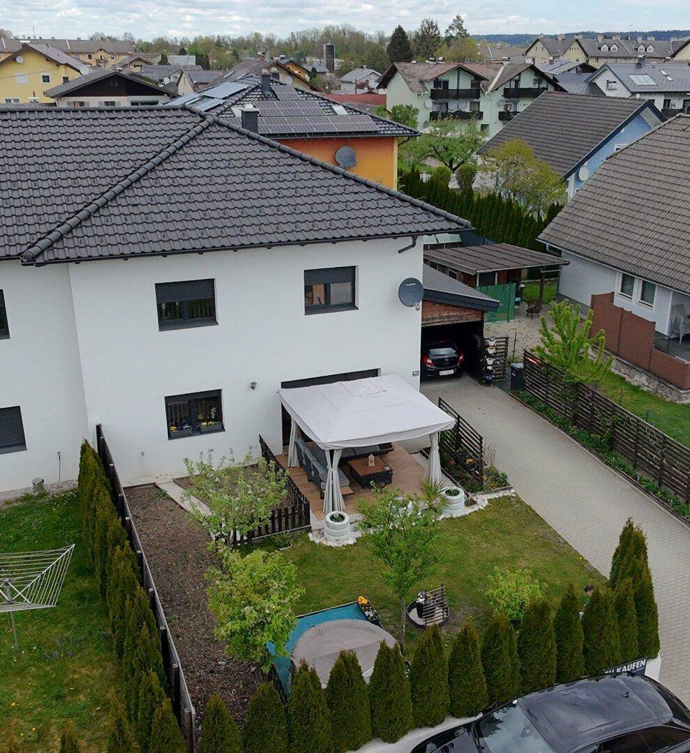 Ansicht des Hauses von der Straße mit Vorgarten, Carport und gepflegter Hecke.