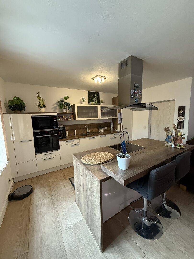 Moderne Küche mit Kochinsel, integriertem Kochfeld und Barhockern, ideal für geselliges Kochen.