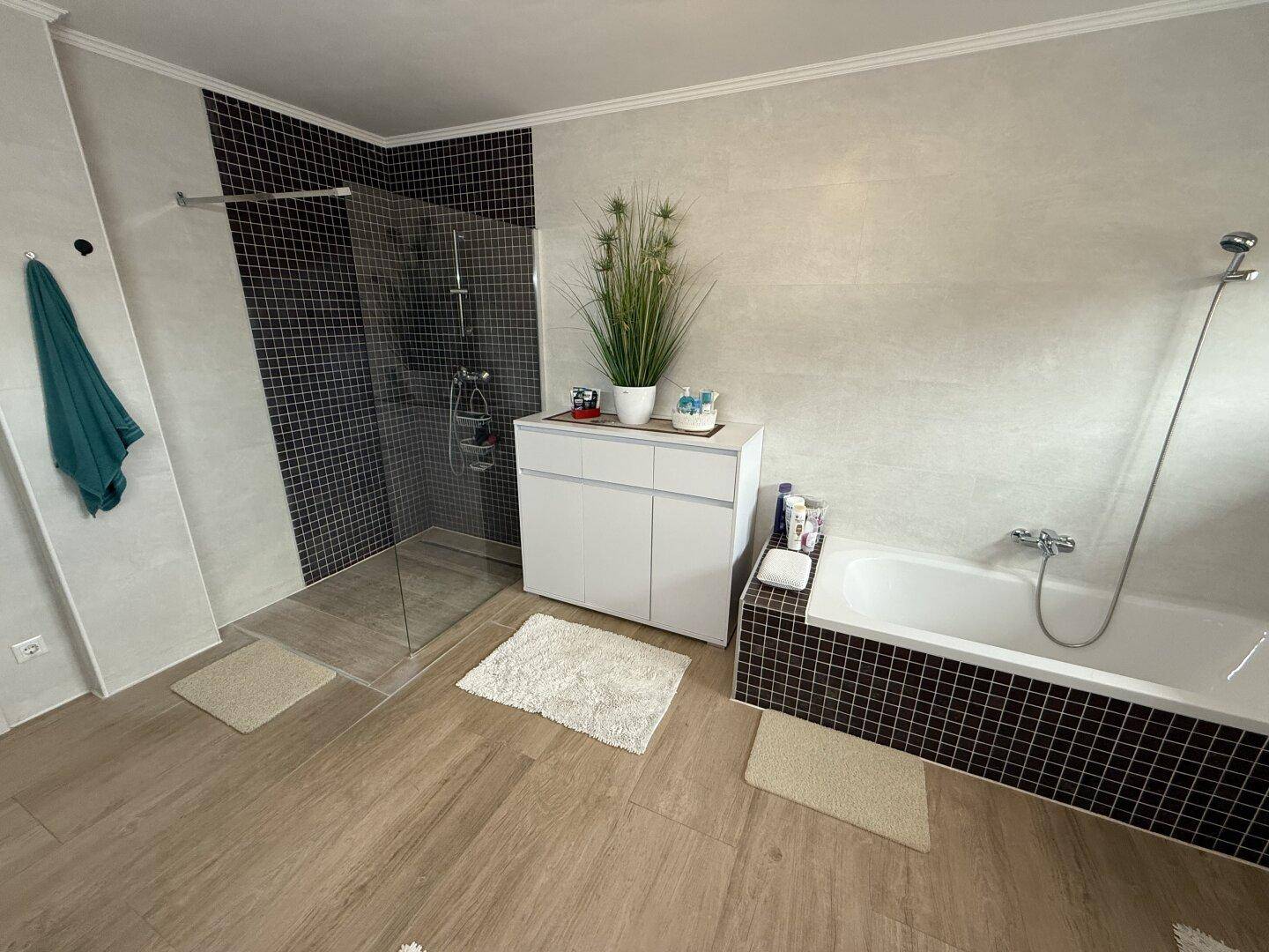 Helles Badezimmer mit begehbarer Dusche, Badewanne und modernen Fliesen in Schwarz-Weiß.