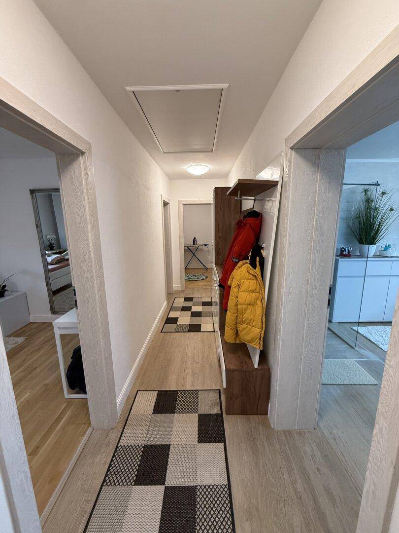 Heller Flur mit Garderobe und Holzoptik-Boden, der zu den weiteren Räumen führt.