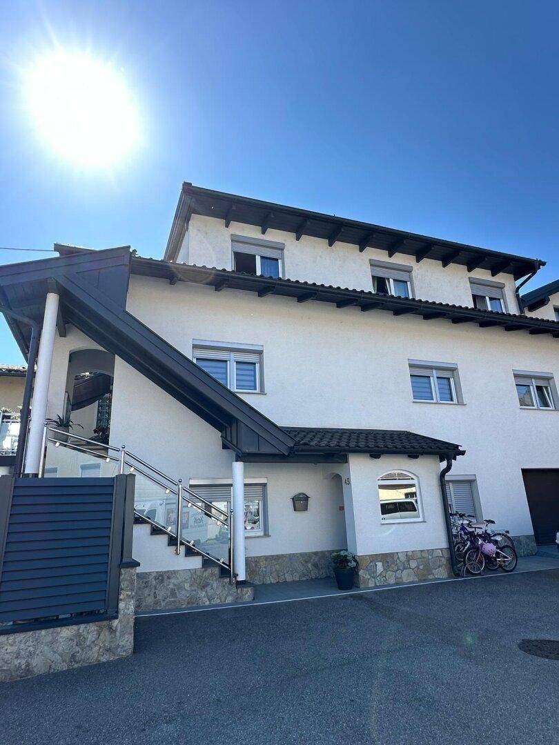 Vorderansicht eines modernen Einfamilienhauses mit weißer Fassade und blauer Himmel.