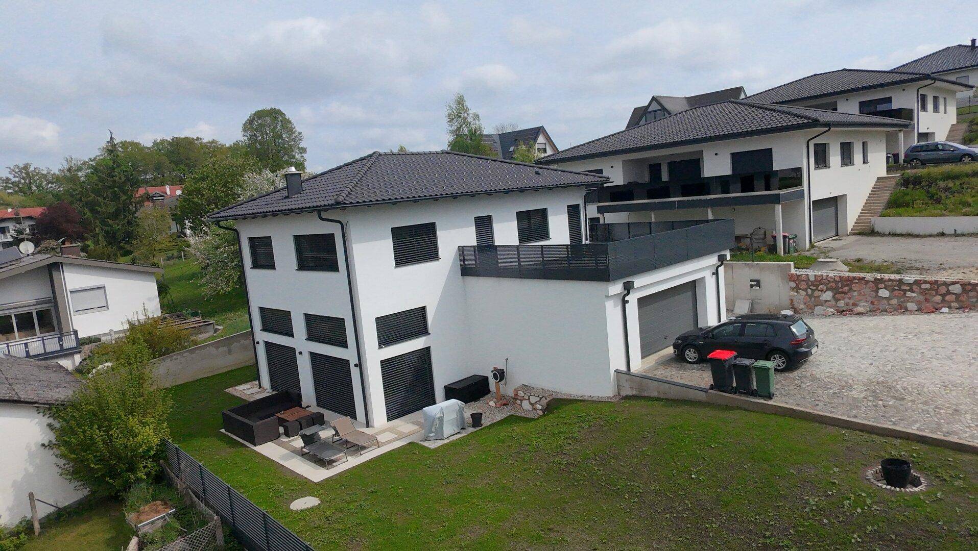 Neubau-Einfamilienhaus mit Garage, Terrasse und Garten in einer modernen Wohnsiedlung.