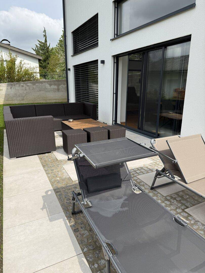 Große gepflasterte Terrasse mit Lounge-Möbeln und Sonnenliegen, ideal zum Entspannen.