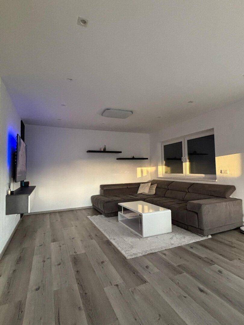Gemütliches Wohnzimmer mit großem Ecksofa, Couchtisch und Laminatboden.