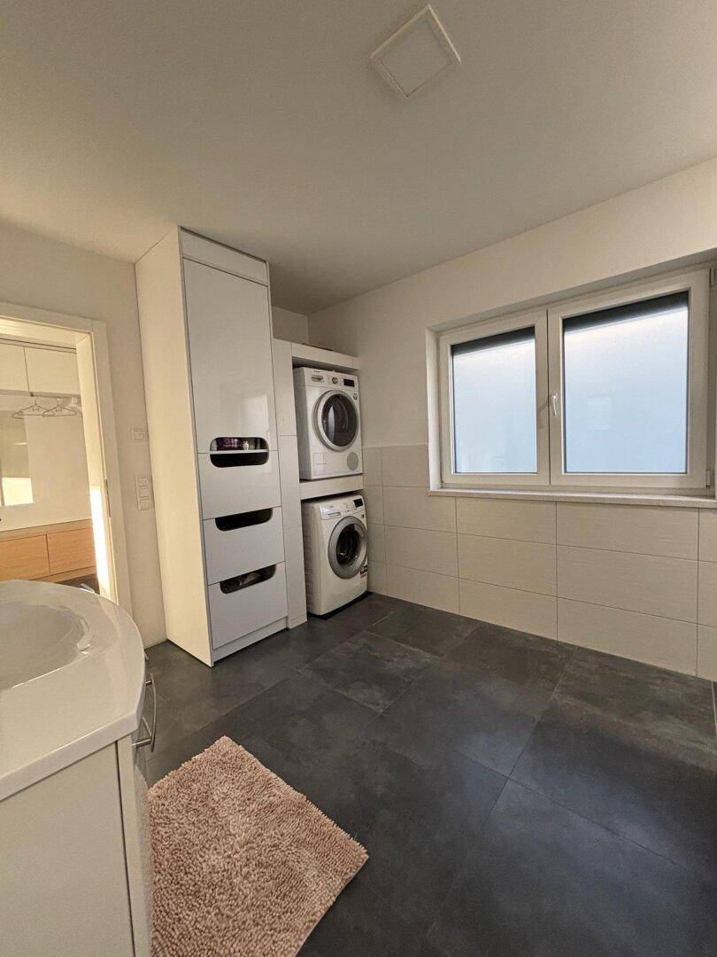 Praktischer Hauswirtschaftsraum mit Waschmaschine, Trockner und Fenster.