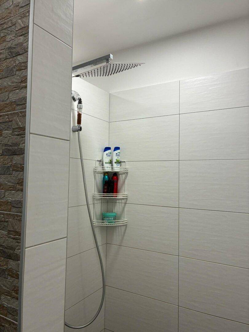 Moderne begehbare Dusche mit großer Regendusche und hellen Fliesen.