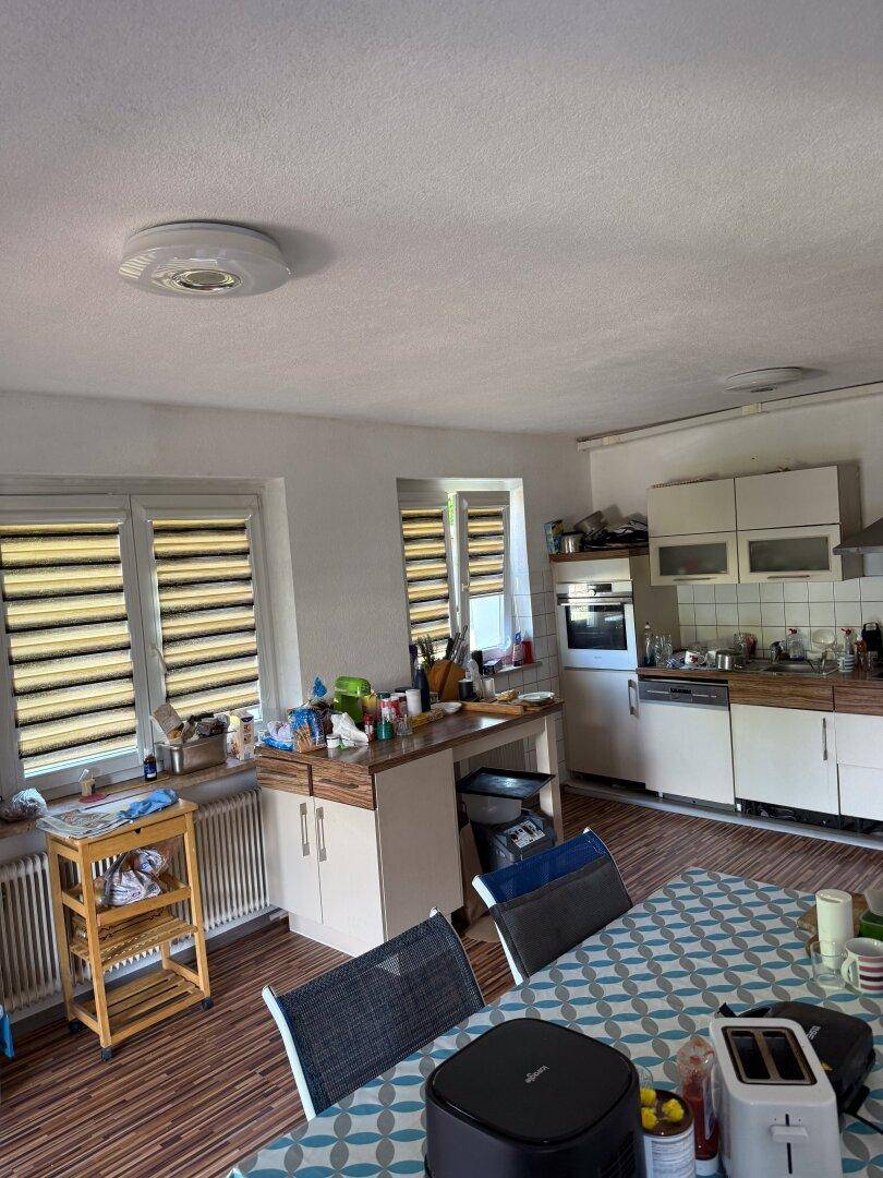 Funktionale Küche mit Essbereich, Einbauschränken und Blick nach draußen durch die Fenster.