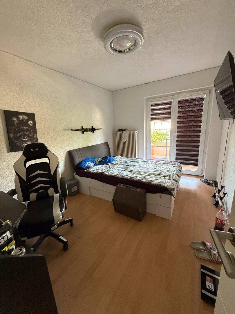 Schlafzimmer mit Bett, Schreibtisch und direktem Zugang zu einem Balkon.
