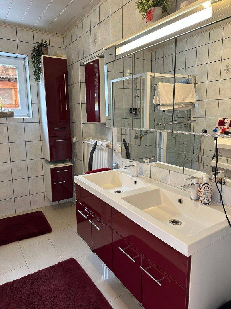 Geräumiges Badezimmer mit Doppelwaschbecken, großen Spiegeln und hellen Fliesen.