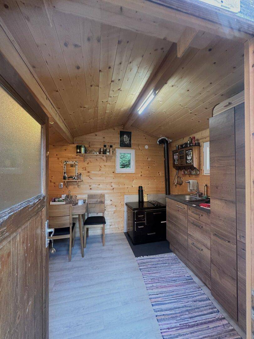 Gemütliche Holzküche in einem Nebengebäude mit kleinem Essbereich und Holzofen.