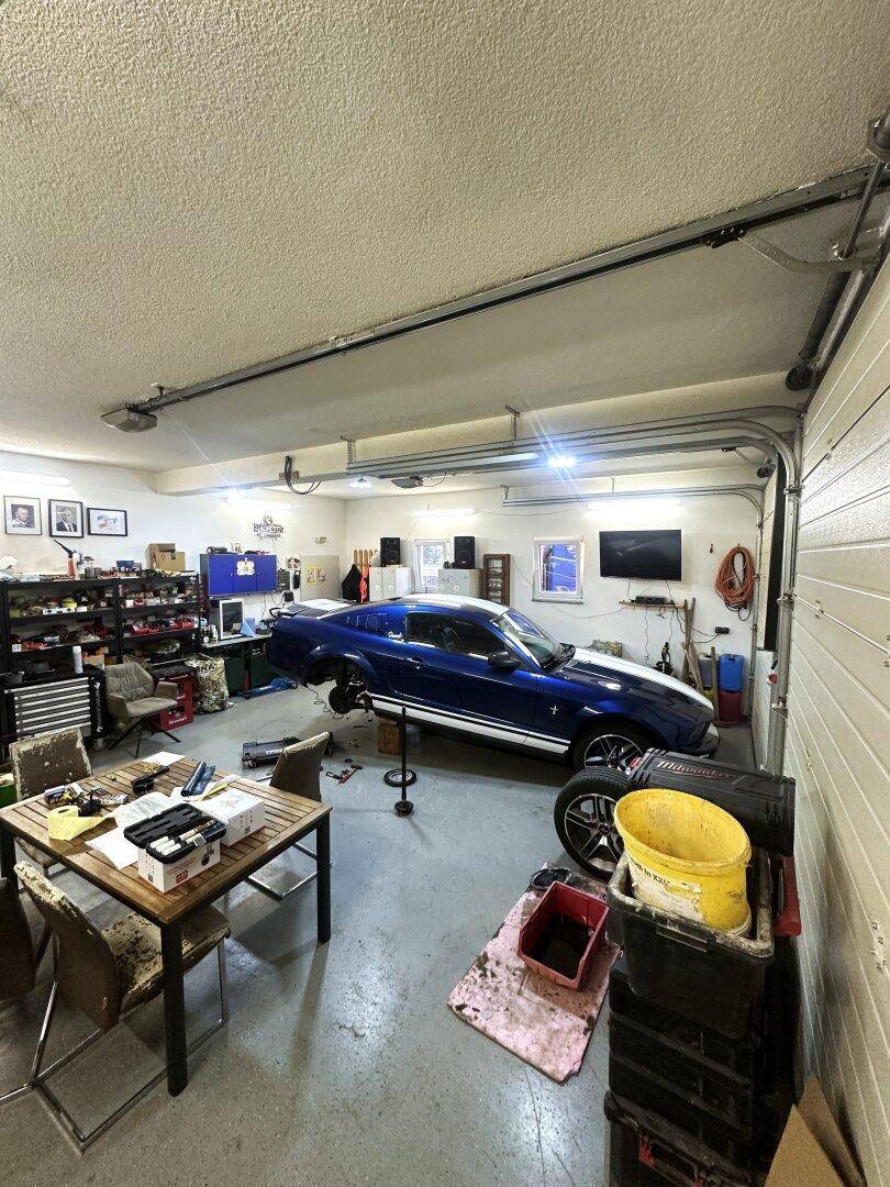 Geräumige Garage mit einem Sportwagen, Werkzeugen und viel Stauraum für Hobbys.