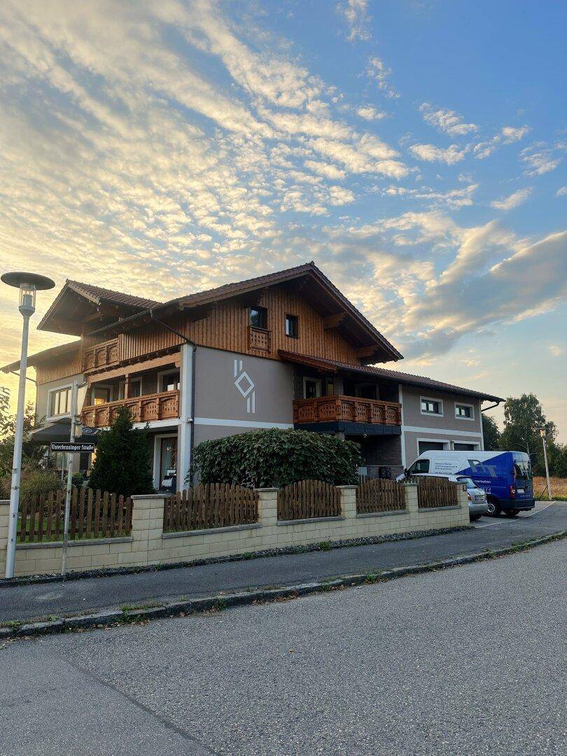 Ansicht des Hauses von der Straße mit traditioneller Holzfassade, Balkonen und einem gepflegten Vorgarten.